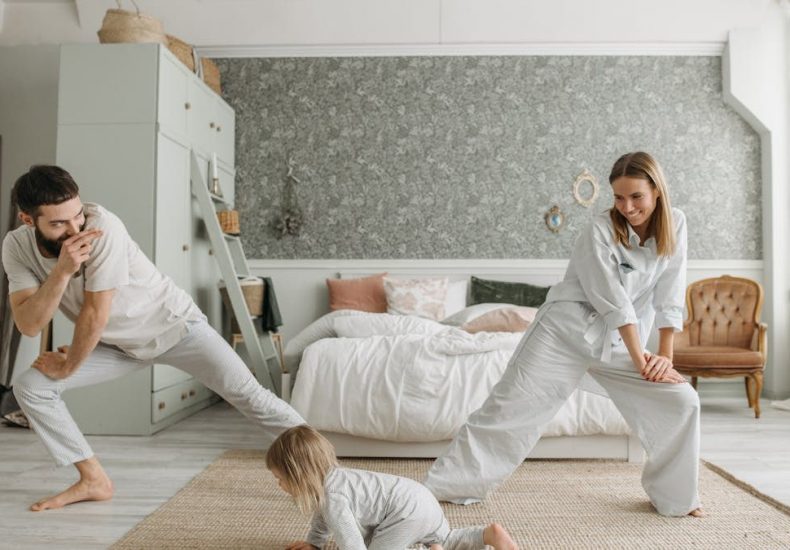 A joyful family bonding through morning stretches in a cozy bedroom setting.