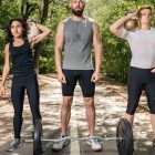 Three adults exercising outdoors with weights, promoting fitness and diversity.