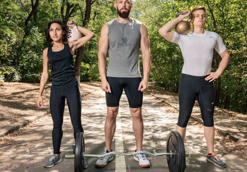 Three adults exercising outdoors with weights, promoting fitness and diversity.