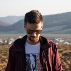 Casual portrait of a bearded man wearing sunglasses in a Slovakian landscape.