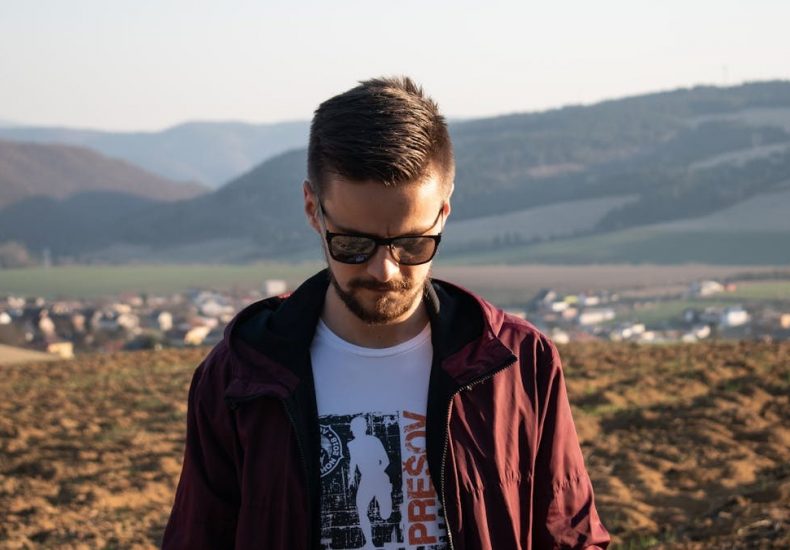 Casual portrait of a bearded man wearing sunglasses in a Slovakian landscape.